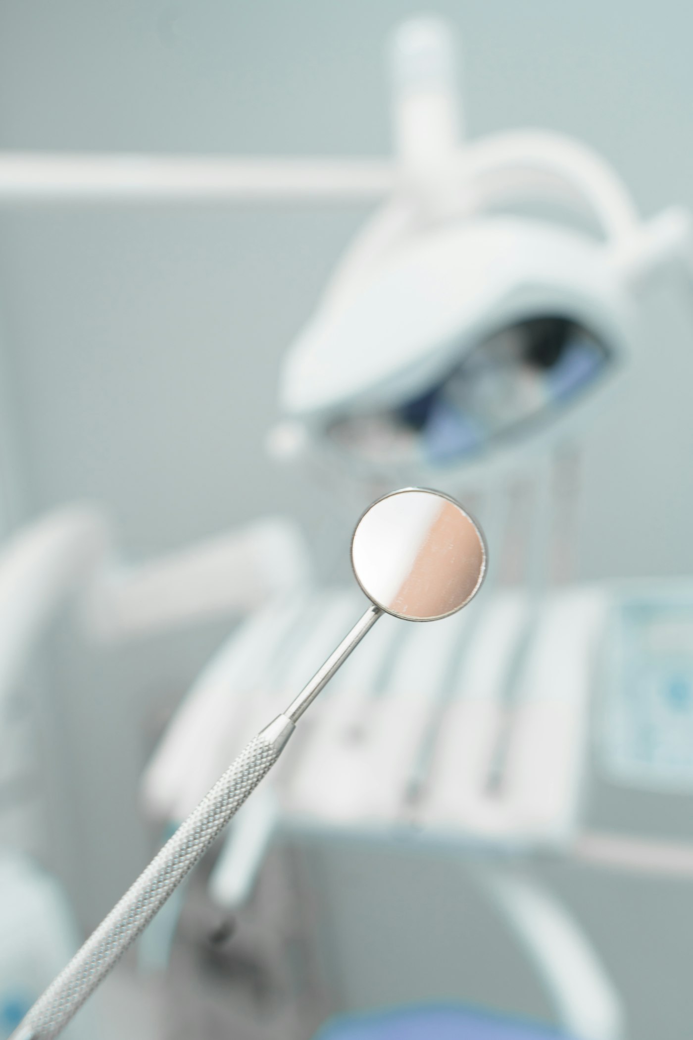 Dental mirror held up in front of a treatment chair
